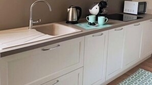 Une cuisine équipée d’un évier, d’une bouilloire, d’une machine à café et d’un four à micro-ondes. On y trouve des placards et des tiroirs sous le plan de travail.