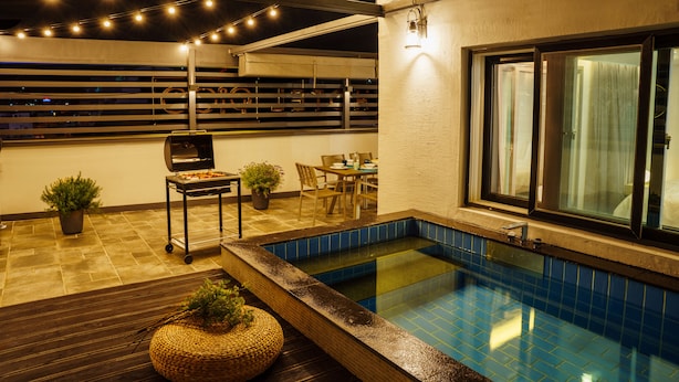 A rooftop pool area with a barbecue grill, seating, and string lights. - Hotel Pico (Tongyeong)
