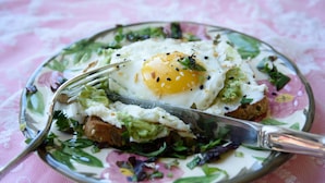Ein Teller mit gebratenem Ei, Avocado und Grünzeug auf einem teller mit Blumenmuster.