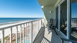 A balcony with a view of the beach and ocean.