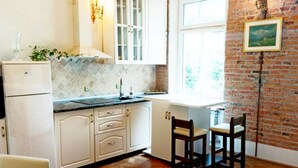 A kitchen with white cabinets, a herringbone wood floor, and a brick wall. - Style, space and security in ultra central location in Brasov (Brașov)