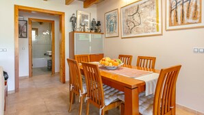 A dining room with a wooden table, chairs, and a fruit bowl. - Country House 'Els Oscols 53' with Sea Views, Wi-Fi and Air Conditioning (Alcudia)