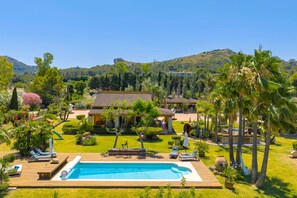 Un complexe hôtelier doté d’une piscine, de chaises longues et offrant une vue sur les collines environnantes.