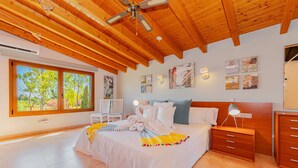 Une chambre bien éclairée, dotée d’un grand lit, d’un plafond en bois et d’œuvres d’art accrochées aux murs.