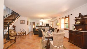 Amplia sala de estar con mesa de comedor, sillas, sofás y una escalera.
