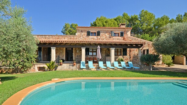 Una casa de piedra de dos pisos con una piscina al frente.
