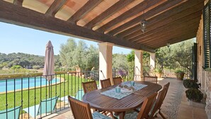 Un patio exterior con piscina, mesa y sillas de madera.