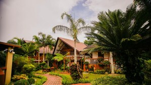 A tropical resort with a paved walkway, palm trees, and a building with a sloped roof. - Hortz Hotels and Resorts (Tagaytay)