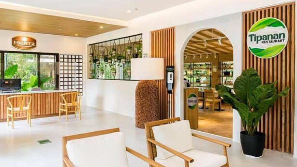 A modern hotel lobby with a reception desk, seating area, and a restaurant entrance. - Hortz Hotels and Resorts (Tagaytay)