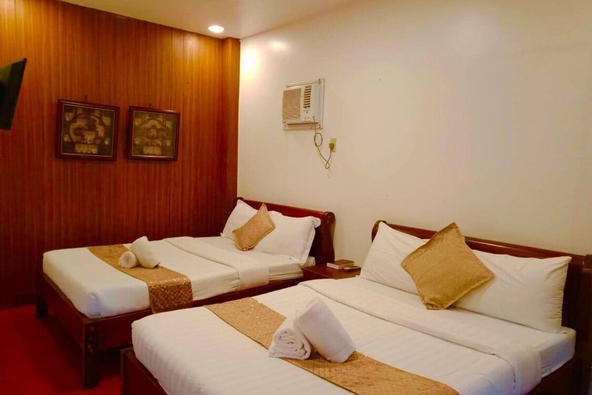 Two single beds with wooden headboards, white linens, and beige decorative pillows.