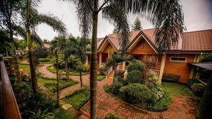 A bungalow with a red-tiled roof, surrounded by lush greenery and a winding brick pathway. - Hortz Hotels and Resorts (Tagaytay)