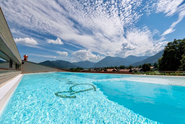 Une piscine à l’eau d’un bleu cristallin, entourée de montagnes et sous un ciel dégagé.