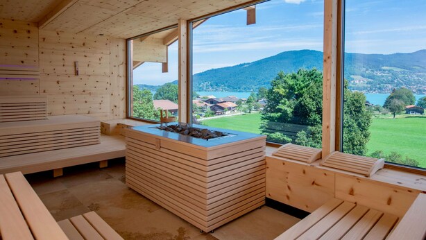 Una baita in legno con ampie finestre, un focolare centrale e panche integrate.