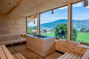 Un intérieur en bois, doté de grandes fenêtres, d’une cheminée centrale et de bancs intégrés.