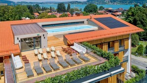 Un edificio moderno con piscina sul tetto, area relax e pannelli solari.