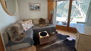 A cozy room with a sofa, a large mirror, a framed picture, and a view of a snowy landscape through a large window.