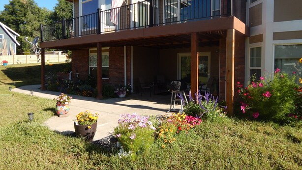 Et toetagers hus med balkon, overdækket terrasse og en have med mange blomster.