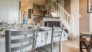A dining area with a table set for four, chairs, a water bottle, and a kitchen in the background.