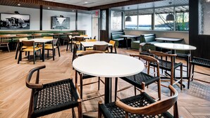 A modern restaurant with wooden flooring, round tables, and black wicker chairs. - Fairfield Inn & Suites by Marriott Klamath Falls (Klamath Falls)