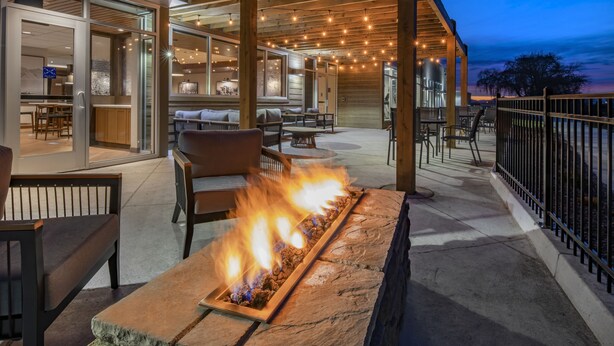 An outdoor patio with a stone fire feature, wooden pergola, and seating area. - Fairfield Inn & Suites by Marriott Klamath Falls (Klamath Falls)