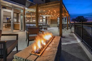 An outdoor patio with a stone fire feature, wooden pergola, and seating area. - Fairfield Inn & Suites by Marriott Klamath Falls (Klamath Falls)