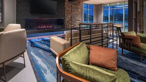 A modern living room with a fireplace, comfortable seating, and a large window offering a view of the city. - Fairfield Inn & Suites by Marriott Klamath Falls (Klamath Falls)