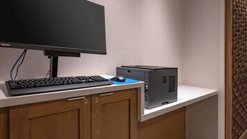 A computer desk with a monitor, keyboard, mouse, and a desktop computer.