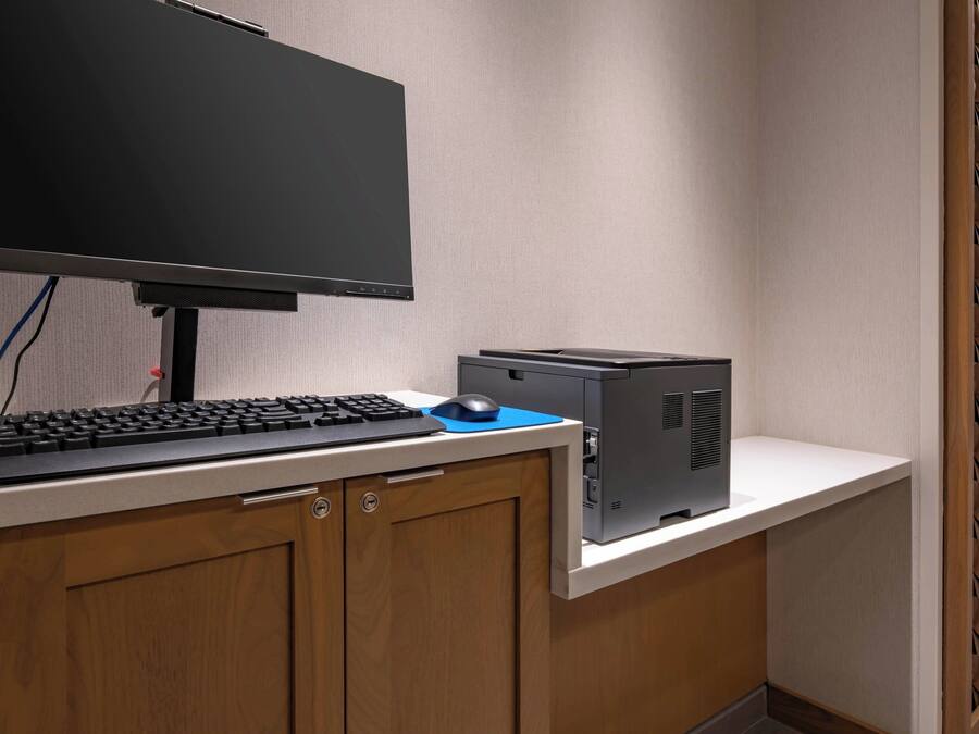 A computer desk with a monitor, keyboard, mouse, and a desktop computer.