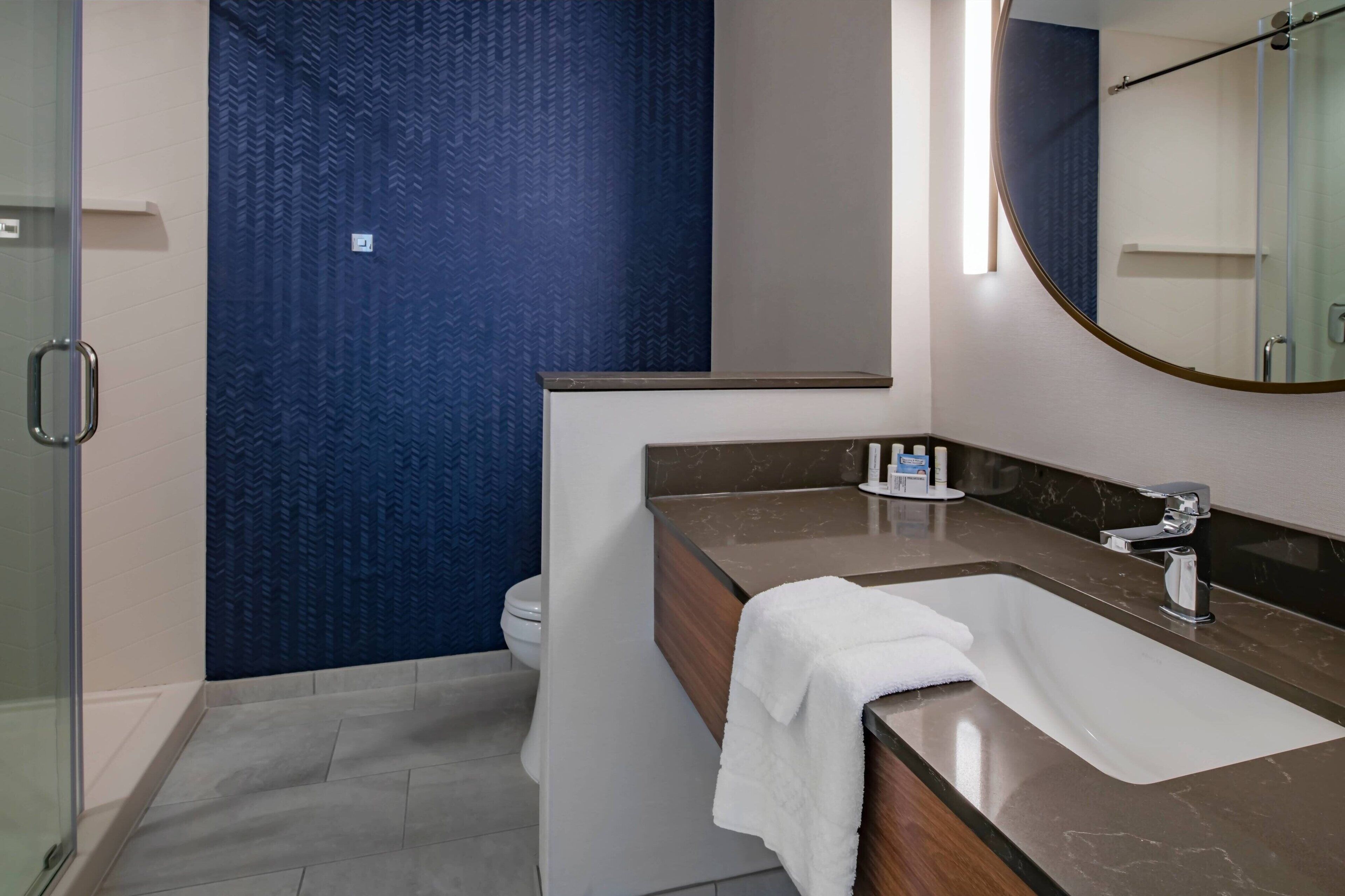 A modern bathroom with a shower, a toilet, and a sink with a towel.