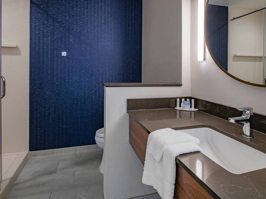 A modern bathroom with a shower, a toilet, and a sink with a towel.