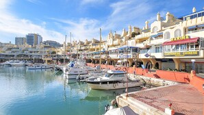 A marina with boats docked, a waterfront promenade, and buildings with various shops and restaurants. - Hill Collection 5 apt, only 1km from Carvajal beach. In Higueron urbanisation (Fuengirola)