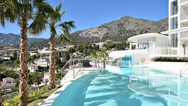 A pool with clear blue water, surrounded by palm trees and a mountainous backdrop. - Hill Collection 5 apt, only 1km from Carvajal beach. In Higueron urbanisation (Fuengirola)
