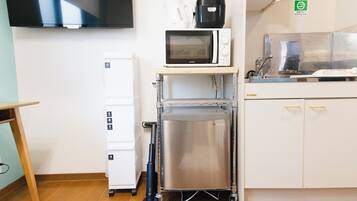 A kitchenette with a microwave, coffee maker, and a stainless steel cart.
