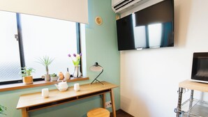 A small, well-lit room with a wooden desk, two stools, a television, and a window with plants. - Near Ikebukuro, Kitchen & Laundry, Fast Wi-Fi, 4min to Station,Many restaurants nearby!! (Tokyo)