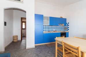 A modern kitchen with blue cabinets, a checkered backsplash, and a wooden dining table.