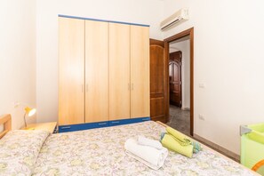 Une chambre à coucher avec un lit, une armoire, un bureau avec une lampe et une chaise verte.