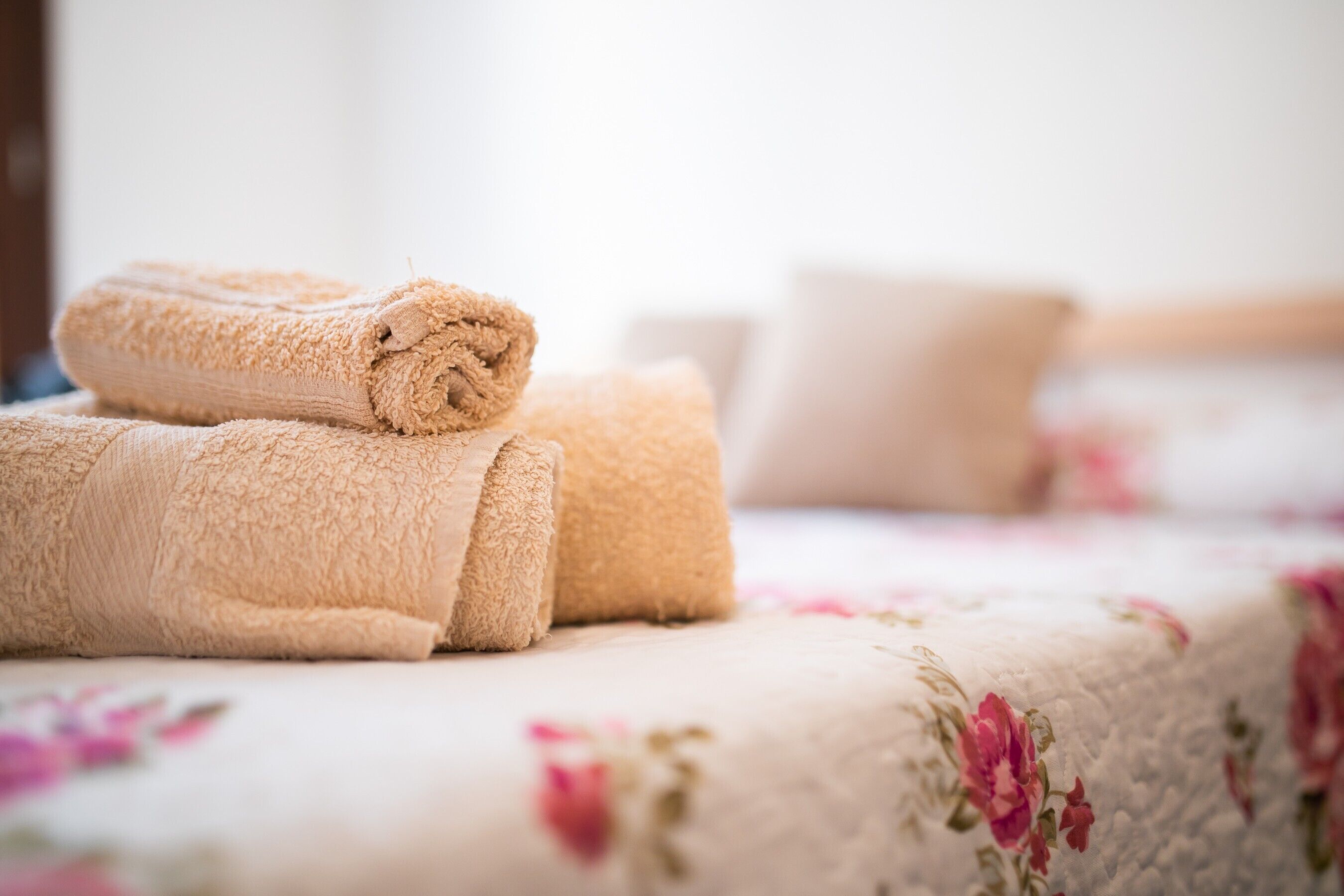 Una toalla beige doblada con cuidado sobre una cama con edredón estampado floral.
