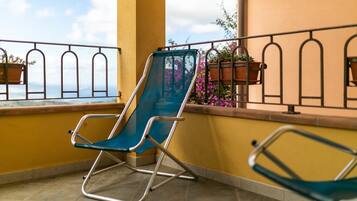 Un balcon avec une chaise bleue, une deuxième chaise et des plantes en pot.