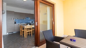 A modern kitchen with a dining area, a sliding glass door leading to an outdoor space, and a small table with chairs.