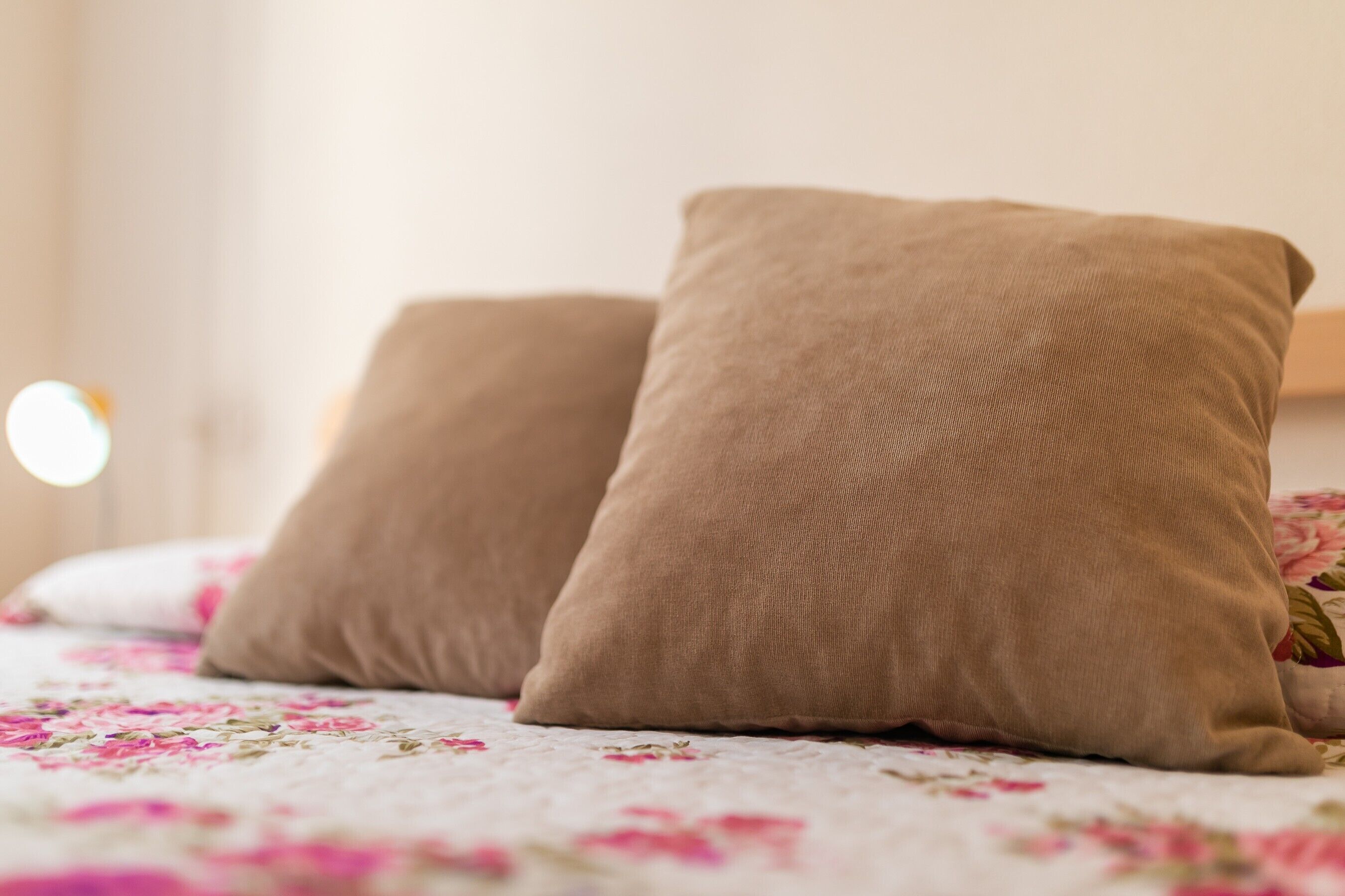 Una cama con ropa de cama floral y dos almohadas beige.