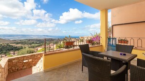 A balcony with wicker furniture, a stone wall, and a view of the countryside.