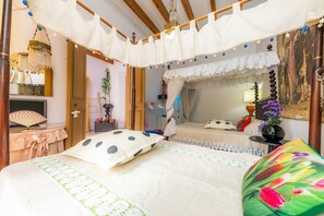 Ein Schlafzimmer mit Bett, Nachttisch, Lampe, Spiegel und einem Fenster mit Vorhängen.