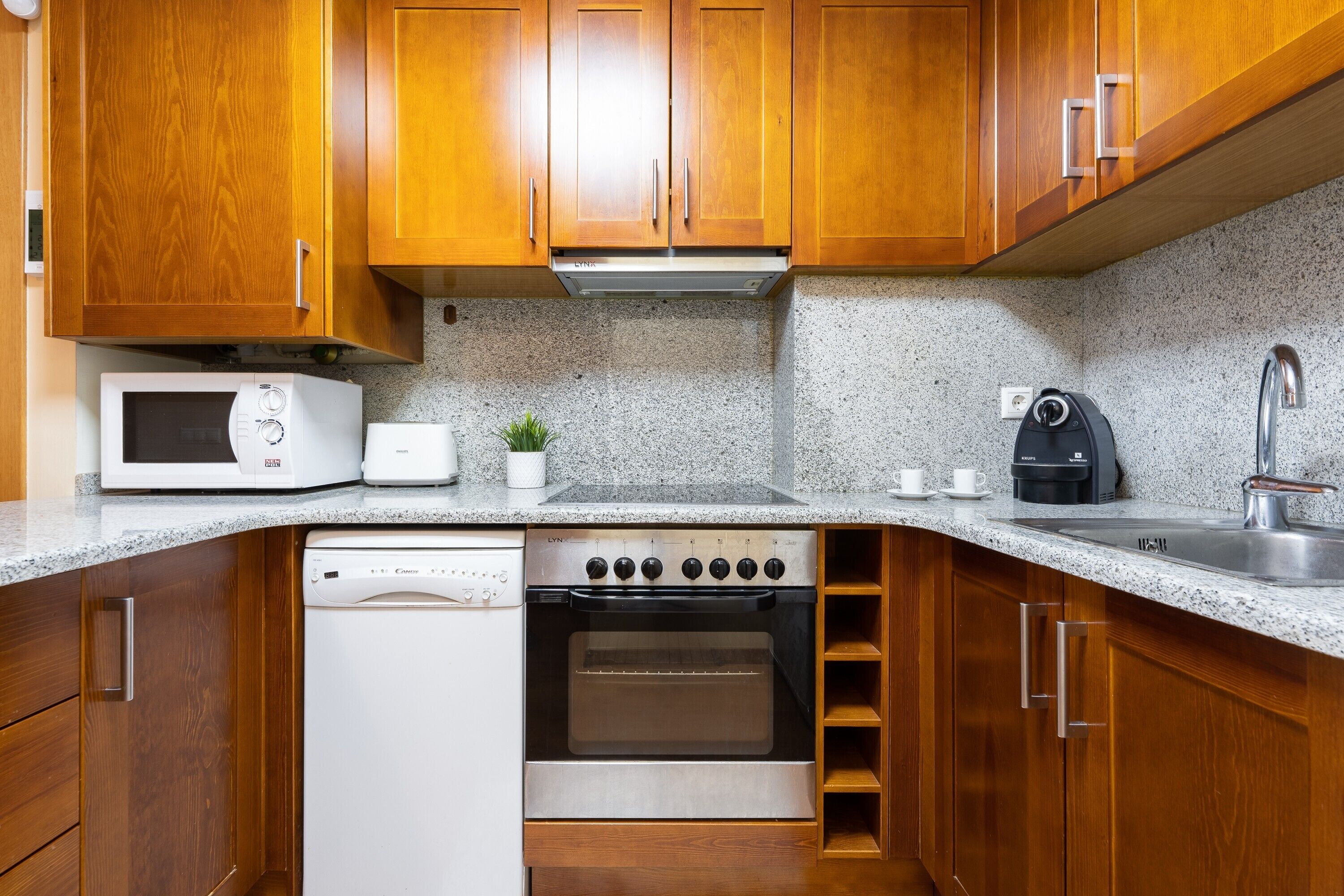 A kitchen with wooden cabinets, a microwave, a stove, a dishwasher, and a coffee maker.