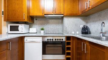 A kitchen with wooden cabinets, a microwave, a stove, a dishwasher, and a coffee maker.