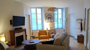 A living room with a fireplace, sofa, armchair, and a television. - "Le Sarment, Beaune historic district downtown (Beaune)