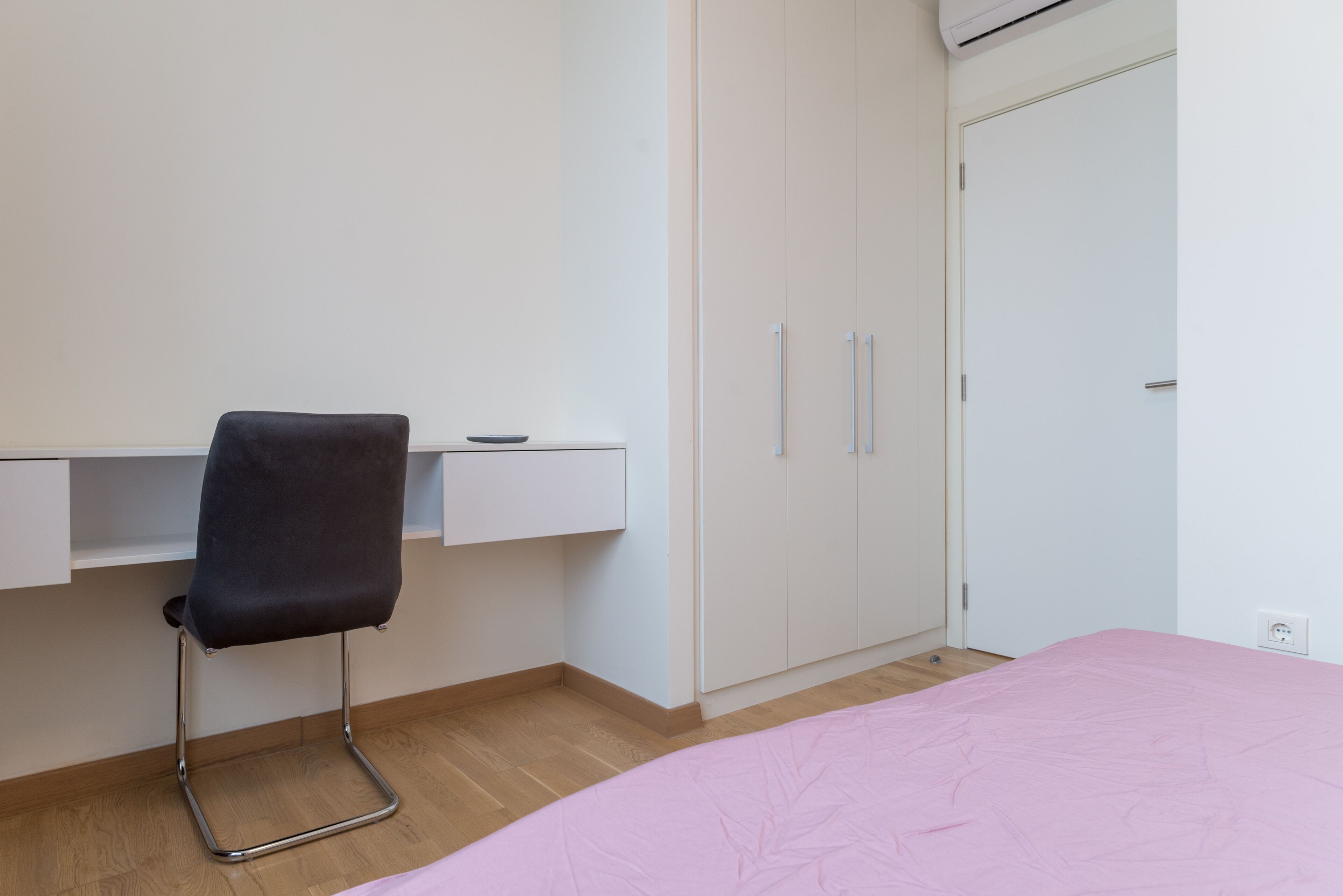 A bedroom with a bed, a chair, a wardrobe, and a desk.