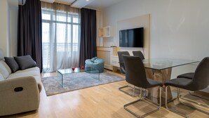 Un salon moderne avec un canapé, une table basse en verre et un coin repas comprenant une table et des chaises en verre.