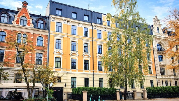Eine Reihe mehrstöckiger Gebäude mit klassischer Architektur, ein Bürgersteig und zwei abgestellte Roller.