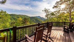 A wooden deck with chairs and a table, overlooking a forested valley. - Altitude Adjustment | Cherry Log, Ga (Cherry Log)