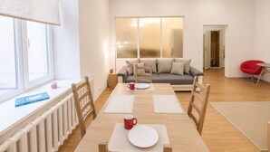 Ein modernes Wohnzimmer mit einer Couch, einem Esstisch mit Stühlen und einem roten Sessel.